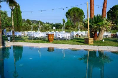 Décoration de table de mariage en extérieur avec chandeliers en verre, fleurs blanches et chaises alignées sur une pelouse.