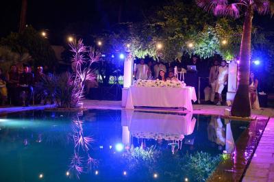 Décoration de table de mariage en extérieur avec chandeliers en verre, fleurs blanches et chaises alignées sur une pelouse.