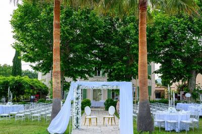 Décoration de table de mariage en extérieur avec chandeliers en verre, fleurs blanches et chaises alignées sur une pelouse.