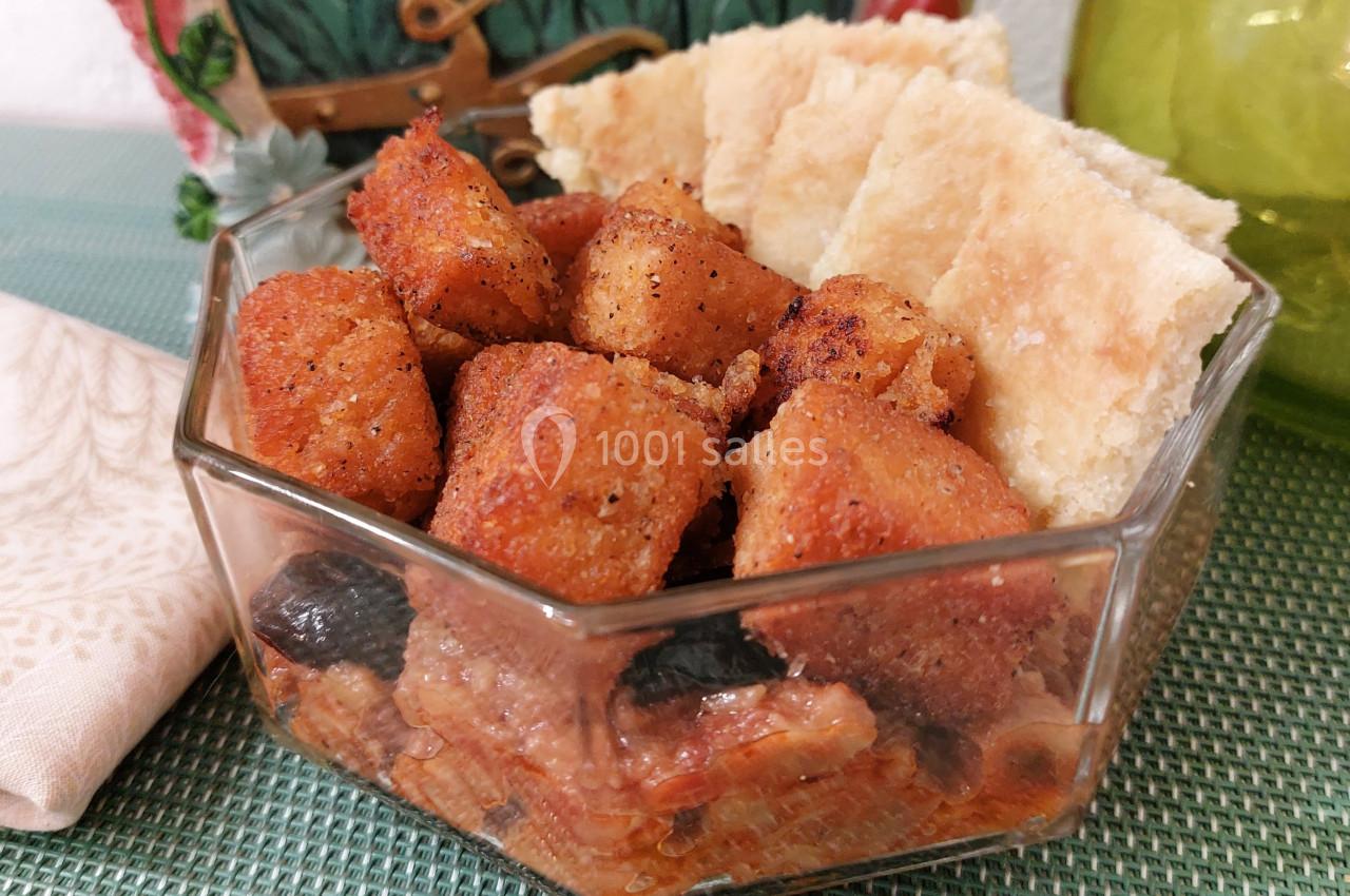 Cubes de pain dorés accompagnés de morceaux de pain plat dans un bol en verre, posés sur une nappe verte.