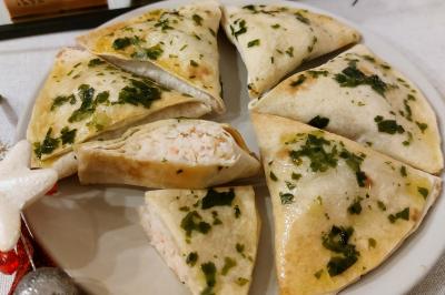 Assiette de triangles de pâte garnis d'une farce crémeuse, décorés de persil et disposés en cercle.