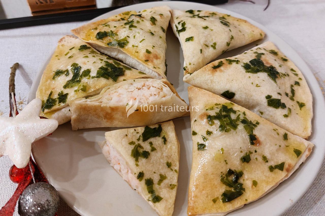 Assiette de triangles de pâte garnis d'une farce crémeuse, décorés de persil et disposés en cercle.