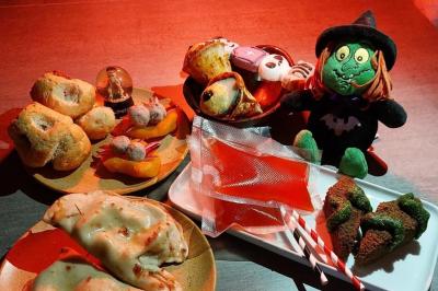 Assortiment de pâtisseries et friandises sur le thème d'Halloween avec une peluche de sorcière en décoration.