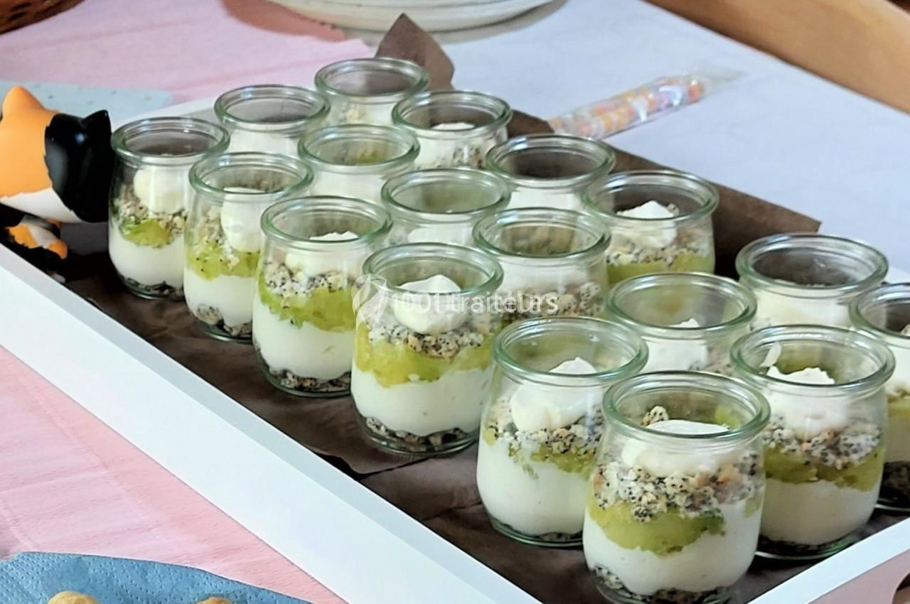 Verrines individuelles composées de couches de fromage blanc, crumble et purée de fruits verts, disposées sur un plateau.