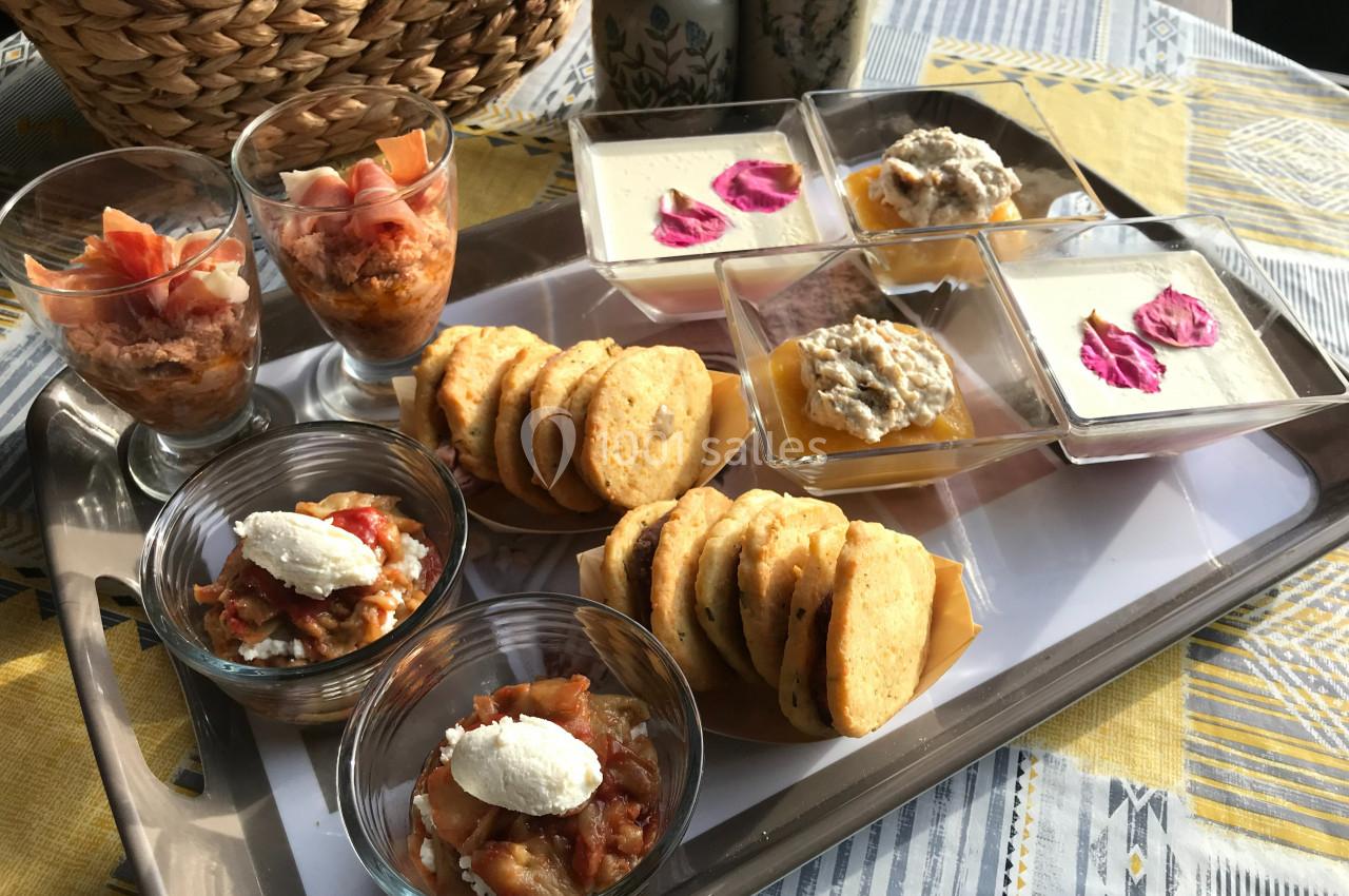 Plateau de verrines salées, biscuits apéritifs et desserts présentés sur une table avec une nappe colorée.