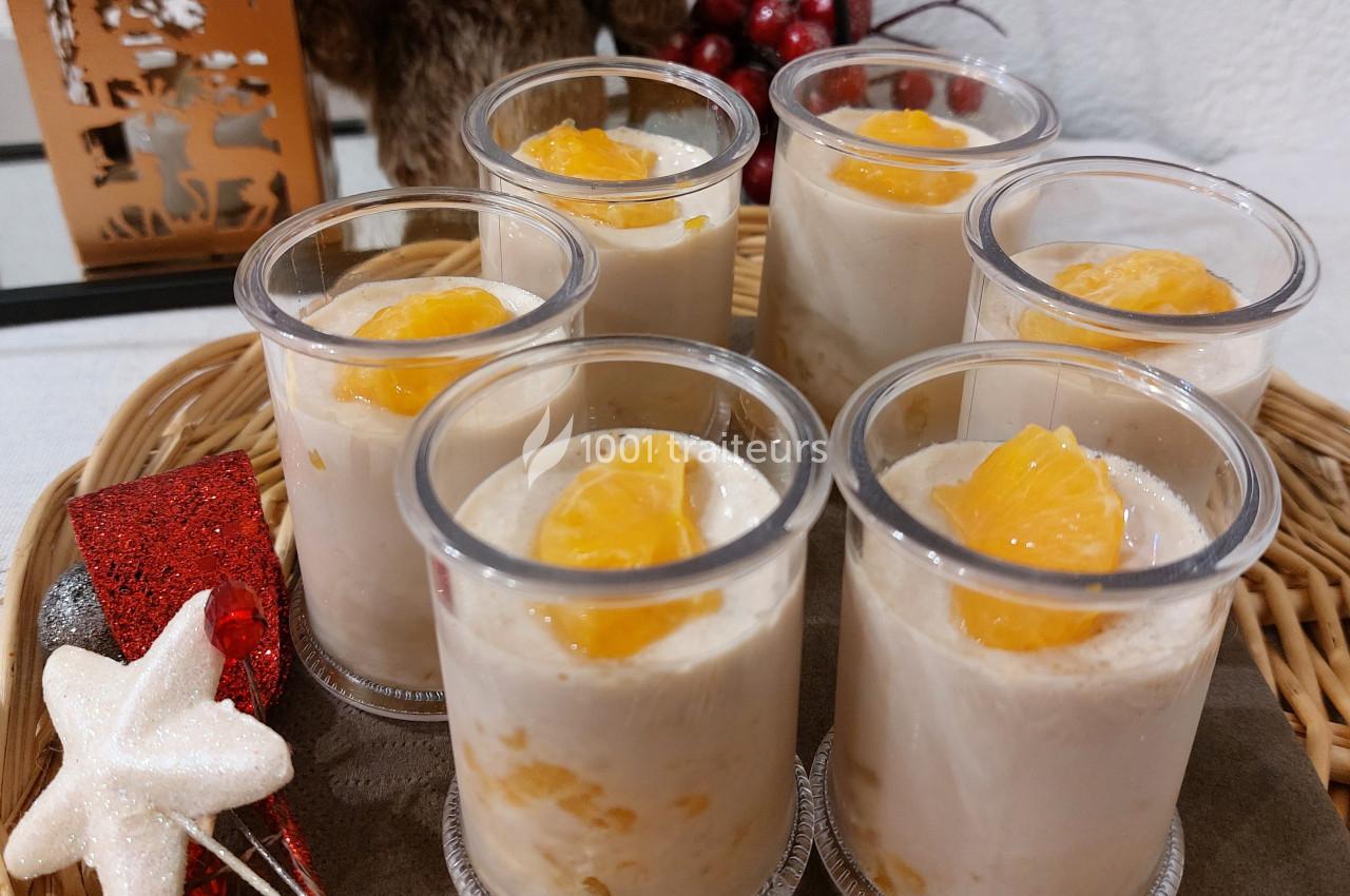 Desserts individuels crémeux garnis de morceaux de mandarine, présentés sur un plateau avec des décorations festives.