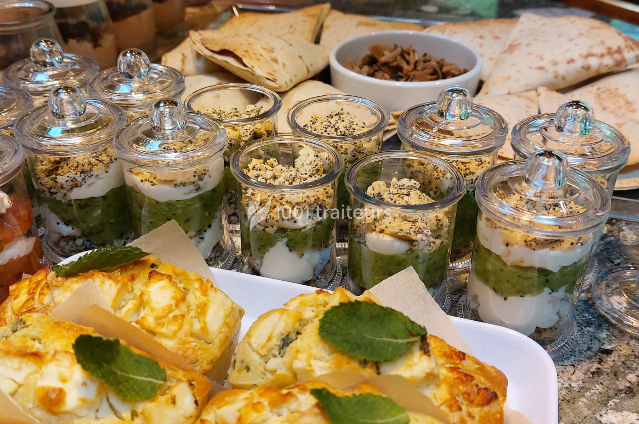 Plateau de verrines salées, pains plats, garnitures et feuilletés au fromage sur une table en pierre.