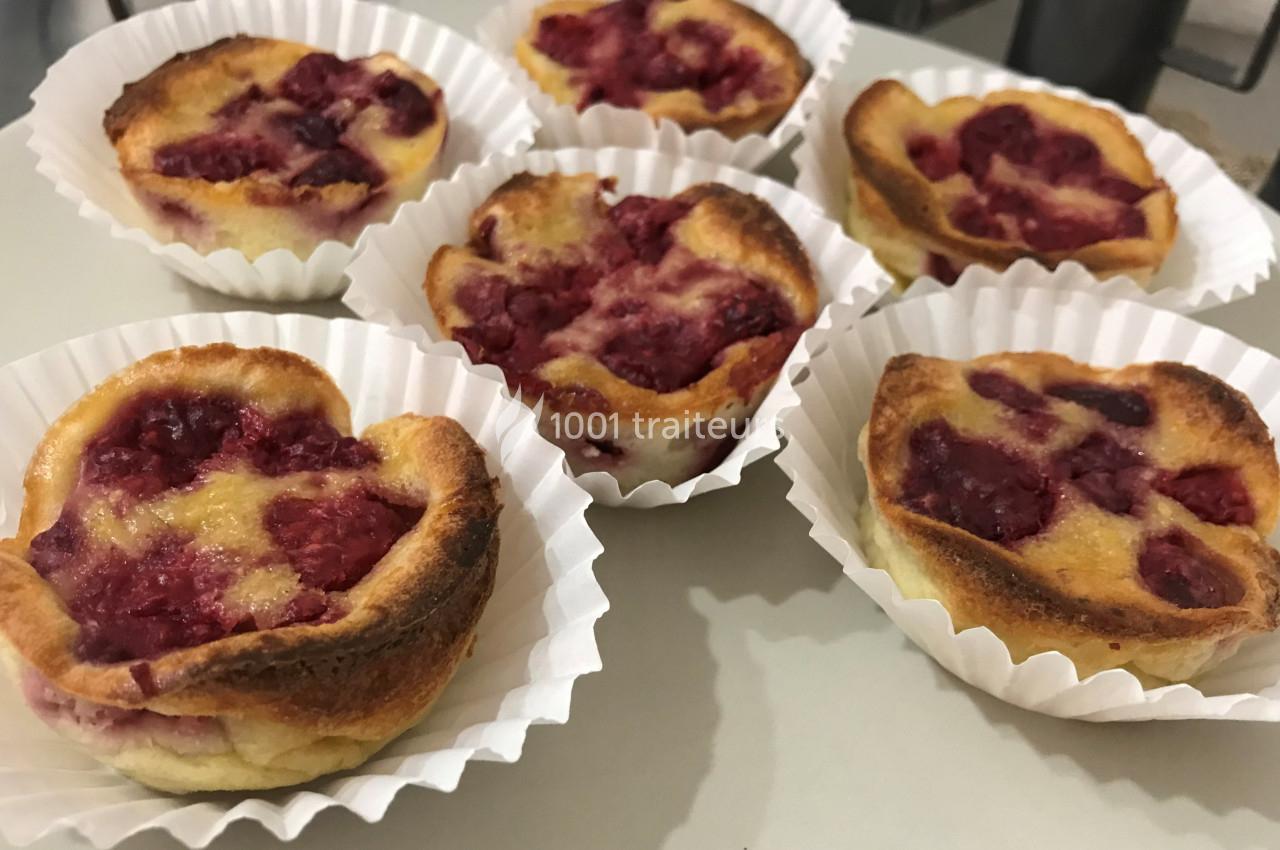 Petits clafoutis aux framboises dorés, présentés dans des caissettes en papier blanc sur une surface claire.