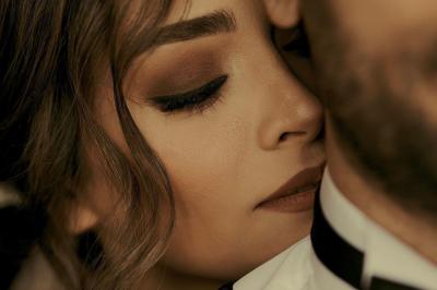 Un couple en tenue de mariage traditionnelle, l'homme en sherwani blanc et la femme en robe brodée rouge.