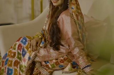 Un couple en tenue de mariage traditionnelle, l'homme en sherwani blanc et la femme en robe brodée rouge.