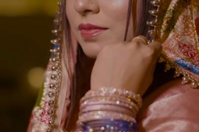 Un couple en tenue de mariage traditionnelle, l'homme en sherwani blanc et la femme en robe brodée rouge.