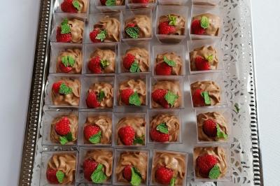 Dessert en portions individuelles avec mousse au chocolat, framboises et feuilles de menthe, disposé sur un plateau argenté.
