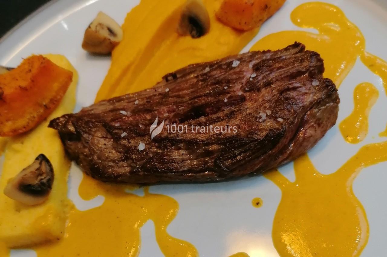 Pièce de viande grillée servie avec purée orange, morceaux de polenta, champignons et sauce jaune.