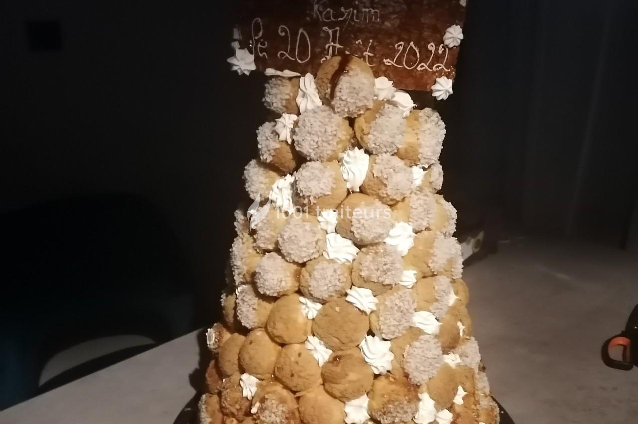 Pyramide de choux garnis de crème, décorée de chantilly et de copeaux, avec une plaque en chocolat personnalisée.