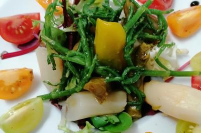 Assiette contenant du saumon fumé, crème, herbes fraîches et garnitures sur une sauce blanche.