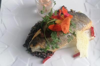 Assiette contenant du saumon fumé, crème, herbes fraîches et garnitures sur une sauce blanche.