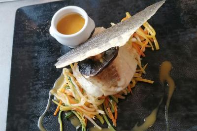 Assiette contenant du saumon fumé, crème, herbes fraîches et garnitures sur une sauce blanche.