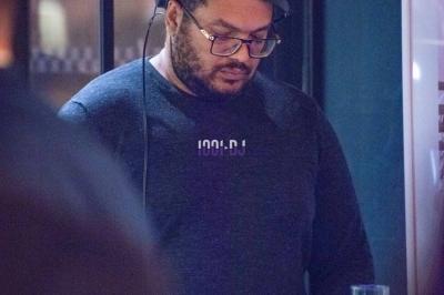 Un homme portant des écouteurs travaille sur un ordinateur portable dans un environnement faiblement éclairé.