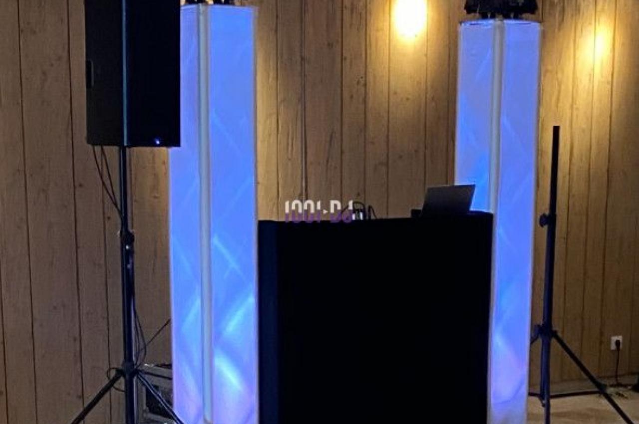 Installation de matériel de sonorisation et d'éclairage dans une salle avec murs en bois et sol clair.