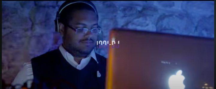 Un homme portant des écouteurs travaille sur un ordinateur portable dans un environnement faiblement éclairé.