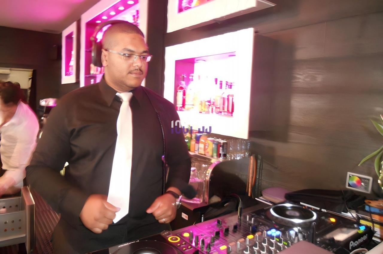 Un DJ mixant de la musique dans un bar avec des lumières roses et un équipement de mixage.