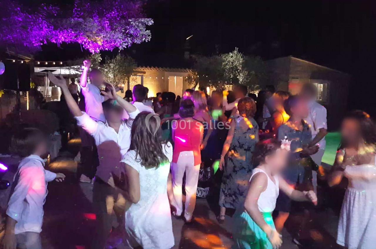 Groupe de personnes dansant lors d'une fête en soirée, éclairée par des lumières colorées.