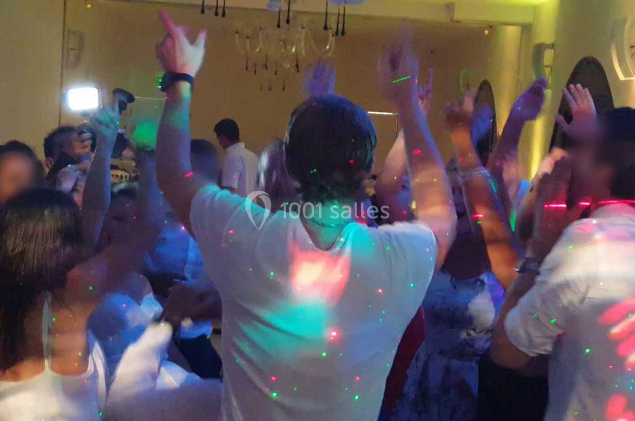 Groupe de personnes dansant dans une salle éclairée par des lumières colorées.