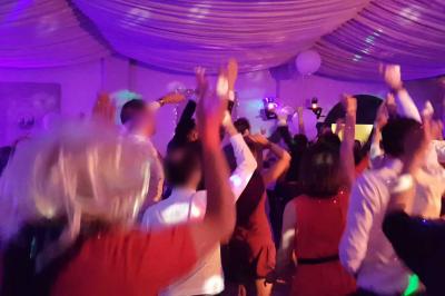 Un homme en costume est porté par une foule festive sous des guirlandes lumineuses, en extérieur de nuit.