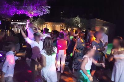 Un homme en costume est porté par une foule festive sous des guirlandes lumineuses, en extérieur de nuit.