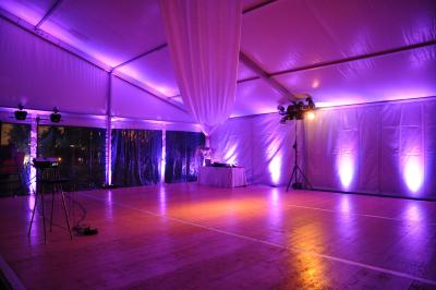 Un homme en costume est porté par une foule festive sous des guirlandes lumineuses, en extérieur de nuit.