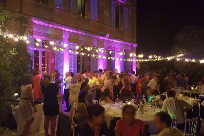 Un homme en costume est porté par une foule festive sous des guirlandes lumineuses, en extérieur de nuit.