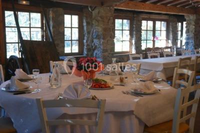 Table élégamment dressée avec chandeliers, verres, bouteilles de vin et serviettes pliées dans un cadre chaleureux.