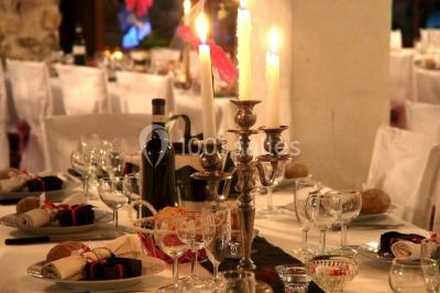 Table élégamment dressée avec chandeliers, verres, bouteilles de vin et serviettes pliées dans un cadre chaleureux.