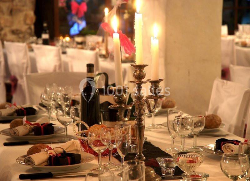 Table élégamment dressée avec chandeliers, verres, bouteilles de vin et serviettes pliées dans un cadre chaleureux.