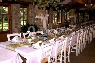 Table élégamment dressée avec chandeliers, verres, bouteilles de vin et serviettes pliées dans un cadre chaleureux.