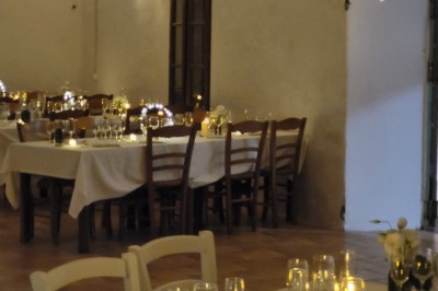 Un poney brun avec une longue crinière se tient sur une pelouse verte près d'arbres et d'un ruisseau.