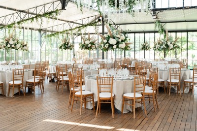 Façade d'un château en pierre et briques entouré d'une pelouse et d'arbres sous un ciel bleu clair.