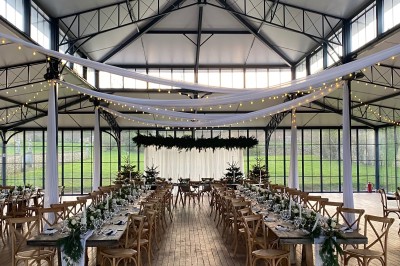 Façade d'un château en pierre et briques entouré d'une pelouse et d'arbres sous un ciel bleu clair.