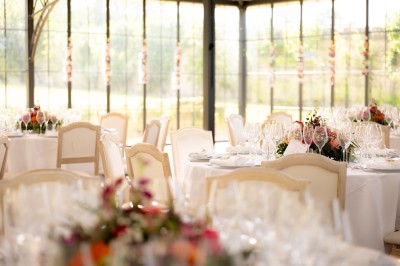 Façade d'un château en pierre et briques entouré d'une pelouse et d'arbres sous un ciel bleu clair.