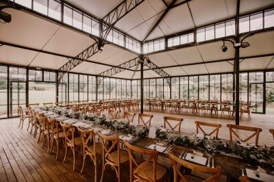 Façade d'un château en pierre et briques entouré d'une pelouse et d'arbres sous un ciel bleu clair.