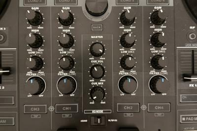 Main ajustant les réglages sur une table de mixage DJ illuminée par des lumières colorées.