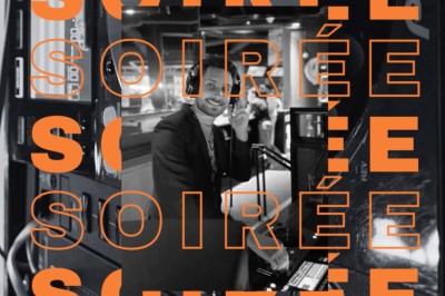 Main ajustant les réglages sur une table de mixage DJ illuminée par des lumières colorées.