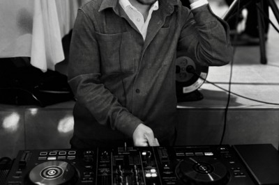 Main ajustant les réglages sur une table de mixage DJ illuminée par des lumières colorées.