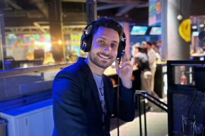 Main ajustant des réglages sur une table de mixage DJ lumineuse avec des écrans et des boutons colorés.