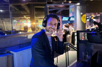 Main ajustant des réglages sur une table de mixage DJ lumineuse avec des écrans et des boutons colorés.