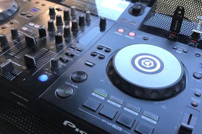 Main ajustant des réglages sur une table de mixage DJ lumineuse avec des écrans et des boutons colorés.