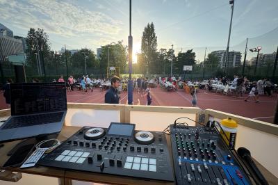 Main ajustant des réglages sur une table de mixage DJ lumineuse avec des écrans et des boutons colorés.