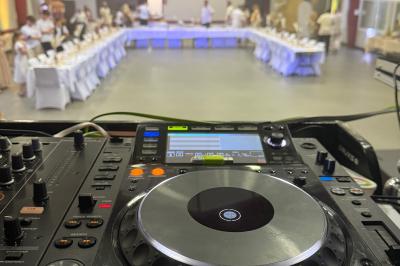 Main ajustant des réglages sur une table de mixage DJ lumineuse avec des écrans et des boutons colorés.