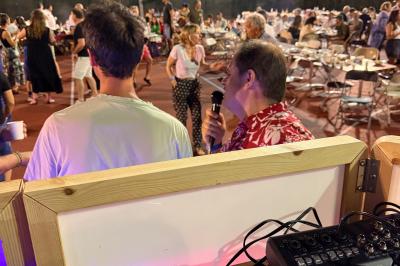 Main ajustant des réglages sur une table de mixage DJ lumineuse avec des écrans et des boutons colorés.