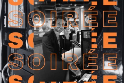 Main ajustant des réglages sur une table de mixage DJ lumineuse avec des écrans et des boutons colorés.